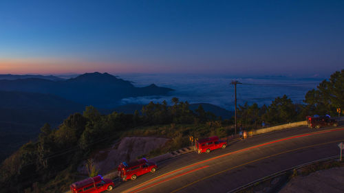 Cars on road against sky at sunset