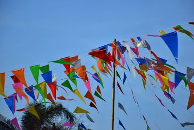 Low angle view of flags against clear blue sky