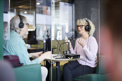 Mature man and woman talking together on radio show or podcast