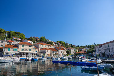 Boats in sea against clear blue sky