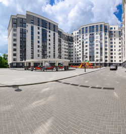 Road by buildings against sky in city