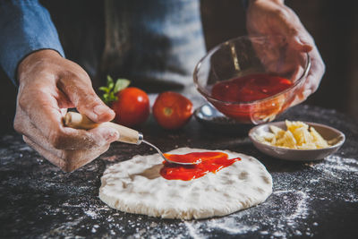 Midsection of man preparing pizza in home