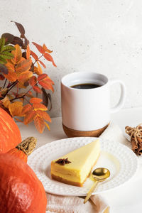 Plate with pumpkin pie piece, cup of tea or coffee, pumpkins and leaves. halloween or thanksgiving.