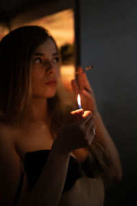 Portrait of young woman holding burning candle