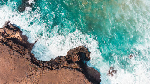 High angle view of waves splashing on rocks