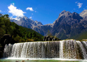 Scenic view of waterfall against mountains