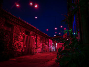 Illuminated street amidst buildings at night