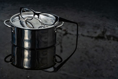 Close-up of eyeglasses and container on wet table