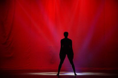 Full length of silhouette man standing against red wall