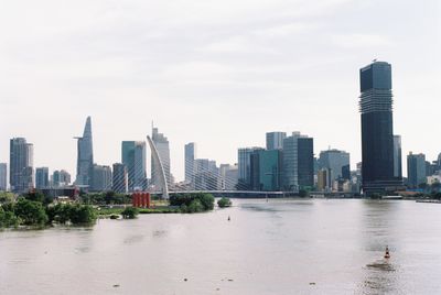 Buildings by river against cloudy sky