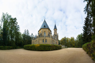 Temple against building and trees against sky