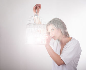 Young woman drinking against white background