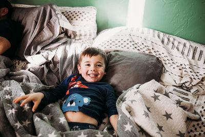 Portrait of smiling boy lying on bed