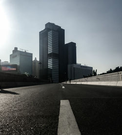 City street by modern buildings against sky