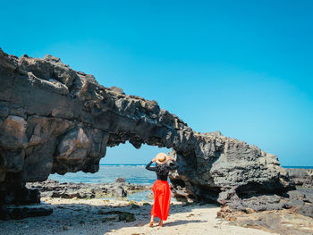 Man standing on rock against blue sky