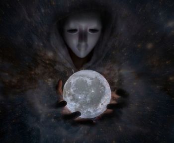 Optical illusion of man wearing mask while holding moon at night