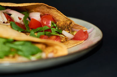 Close-up of pizza on plate against black background