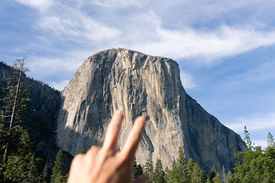 Midsection of person on rock against sky