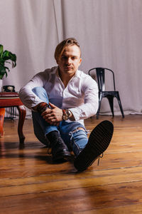 Portrait of young man sitting on chair at home