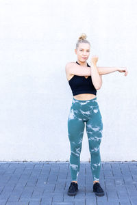 Portrait of young woman standing against wall