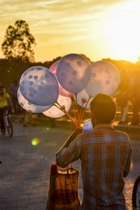 Rear view of people standing against sky during sunset