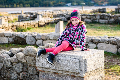 Portrait of girl sitting on seat at old ruins