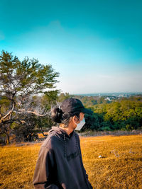 Side view of man standing on field against clear sky