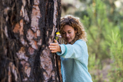 Girl holding tree trunk in forest