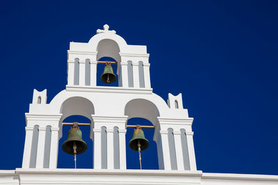 Traditional bell tower of the churches in santorini island against a deep blue sky