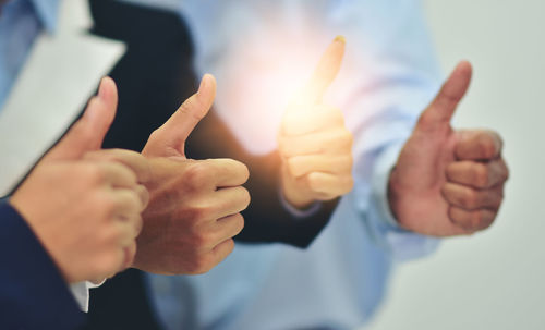 Midsection of business people showing thumbs up signs