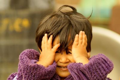 Close-up of cute playful girl covering eyes