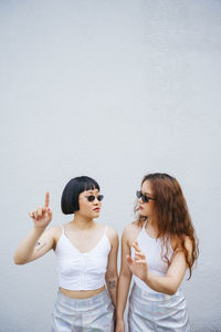 Lesbian couple gesturing while standing against wall outdoors