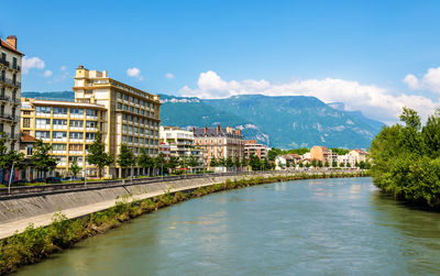 View of buildings at waterfront against cloudy sky