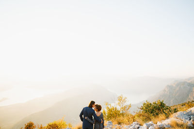 Rear view of couple on mountain against sky