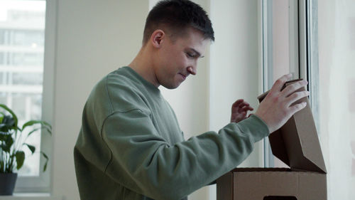 Side view portrait of young man standing at home