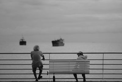 Rear view of people by railing against sky