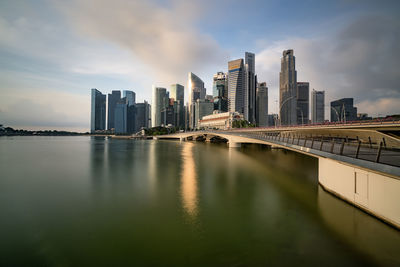 City at waterfront against cloudy sky