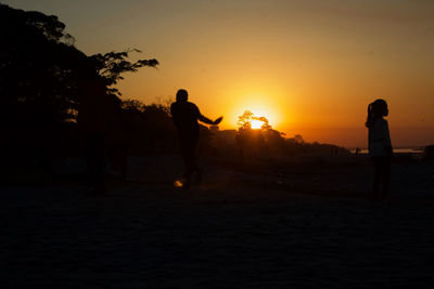 Silhouette man standing on beach against sky during sunset