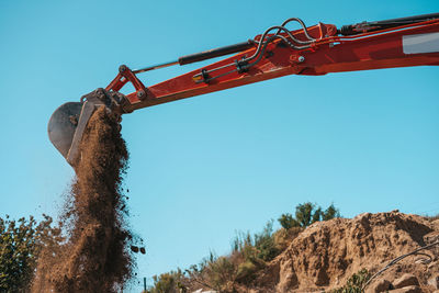 Low angle view of rusty metallic structure on field against clear sky