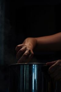 Cropped hands of woman holding container in darkroom