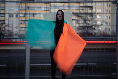 Young woman with umbrella against blurred buildings