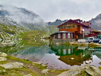 Houses by lake and mountains against sky