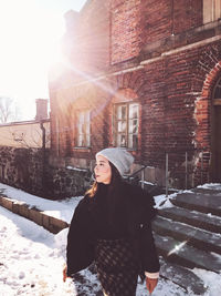 Woman standing by building during winter