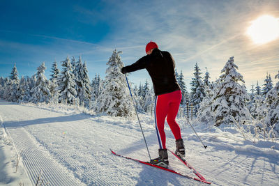 Man skiing on snowy field against sky during winter