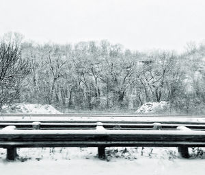 Railroad track by trees against clear sky during winter