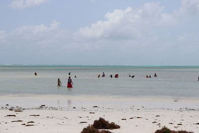 Group of people in sea against sky