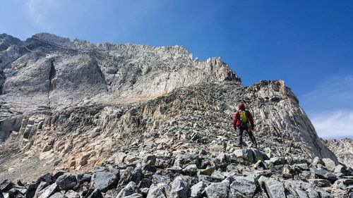 Man standing on rock against sky