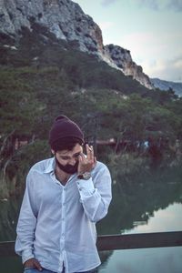 Man smoking cigarette against lake