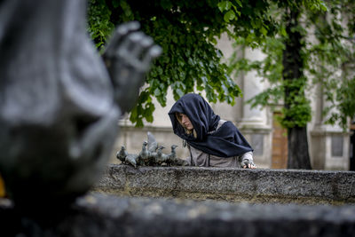 A woman in a black scarf by a fountain 