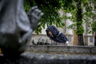 Man with umbrella on retaining wall against trees